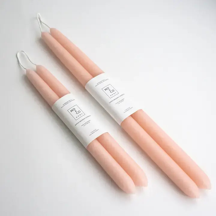 Set of three peach-colored candles with white labels on a light gray background
