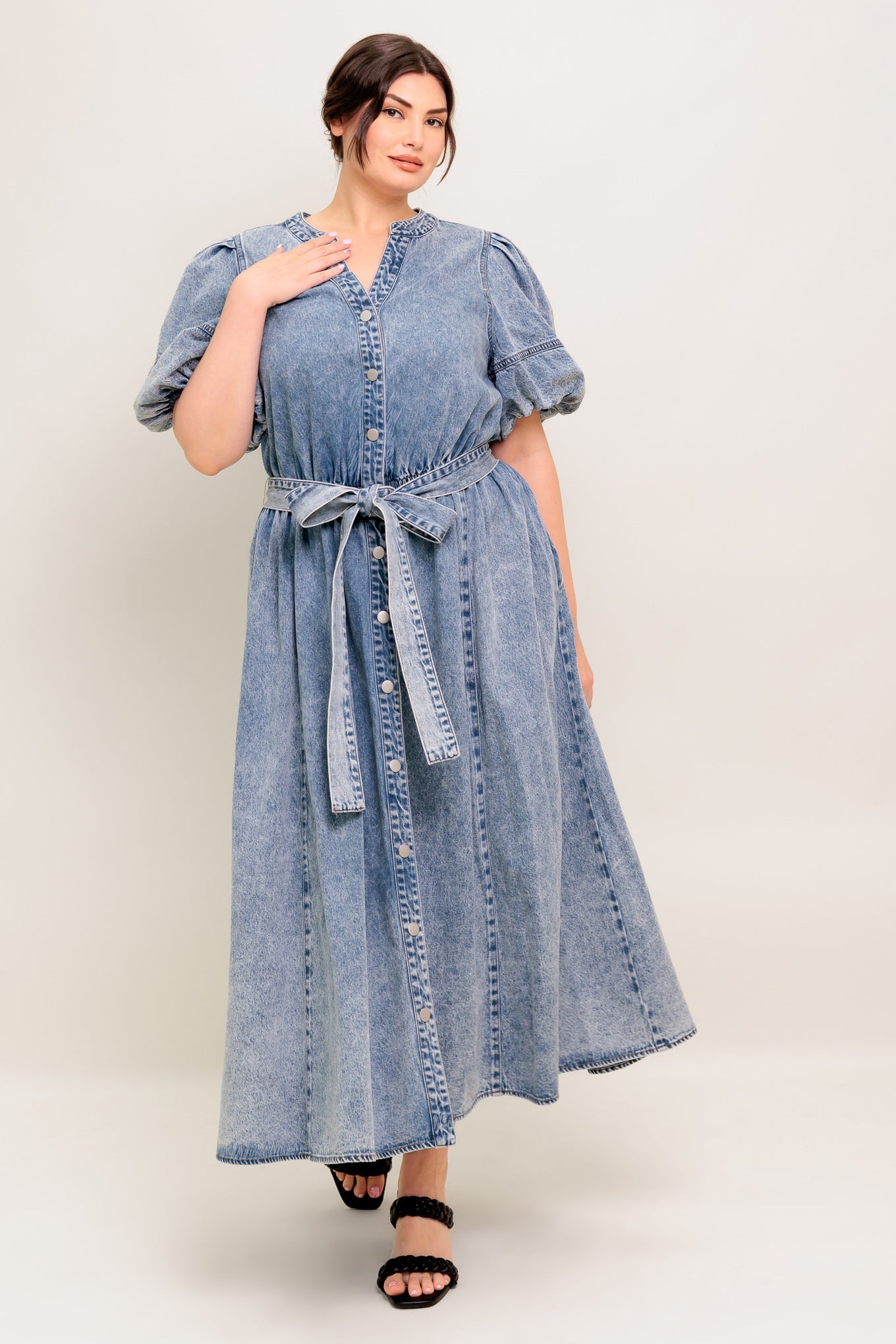 A washed denim midi dress featuring china collar, front button down, short puff sleeve, self sash and full skirt.