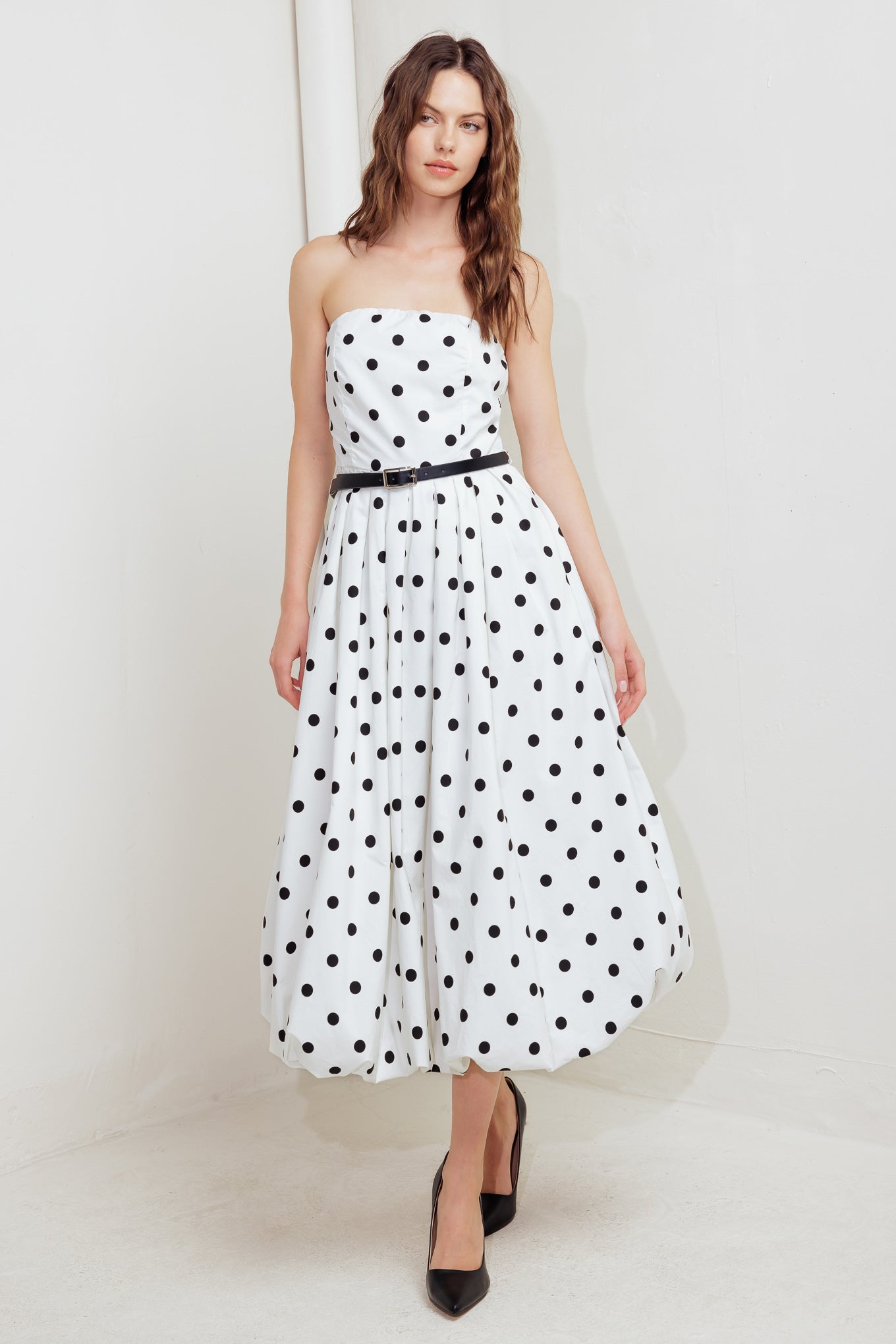 A polka dotted printed woven midi dress featuring strapless, contrasting belt, full skirt, bubble hemline and back zipper closure