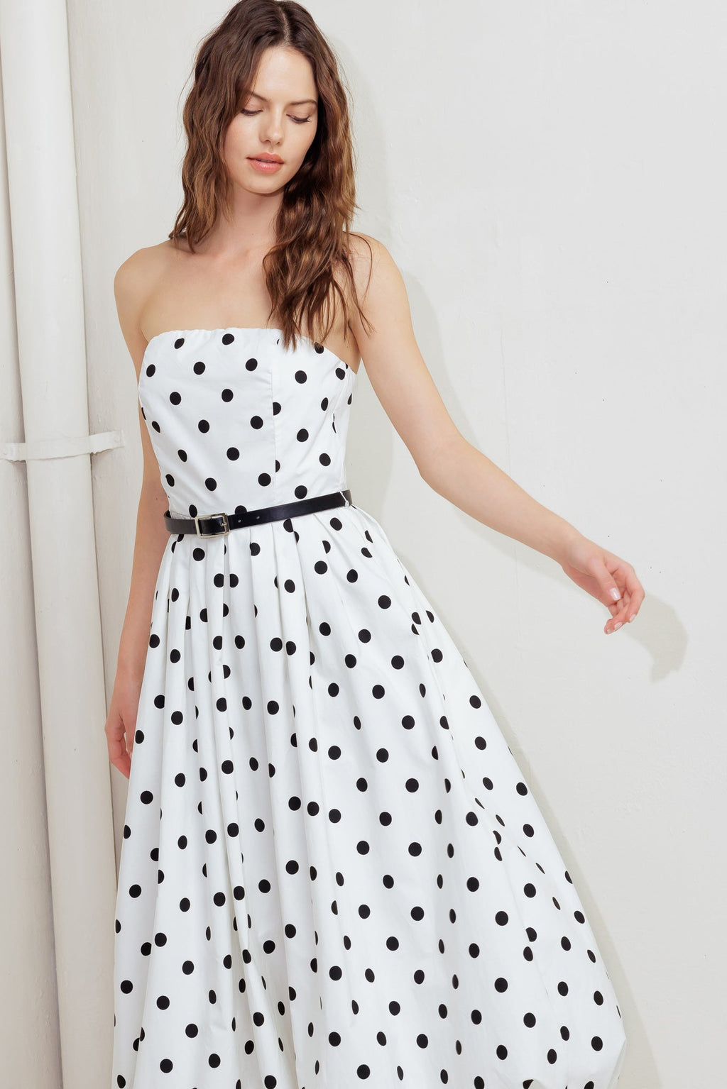 A polka dotted printed woven midi dress featuring strapless, contrasting belt, full skirt, bubble hemline and back zipper closure