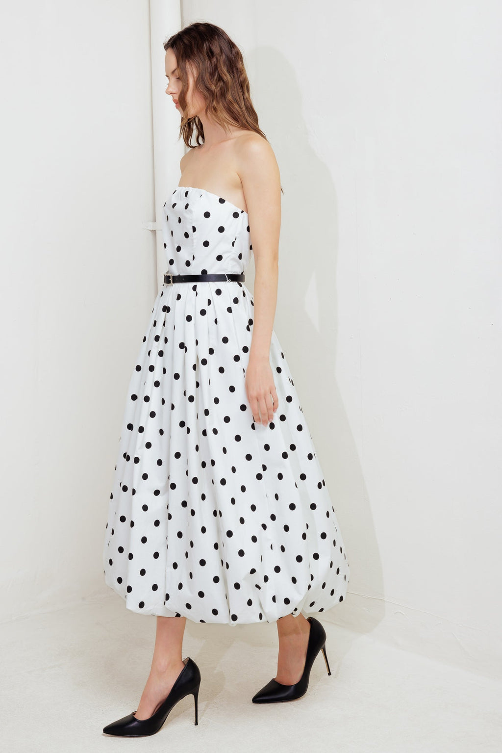 A polka dotted printed woven midi dress featuring strapless, contrasting belt, full skirt, bubble hemline and back zipper closure