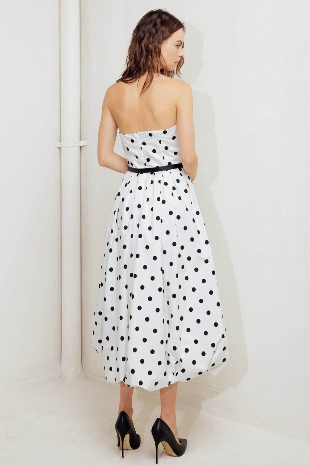 A polka dotted printed woven midi dress featuring strapless, contrasting belt, full skirt, bubble hemline and back zipper closure