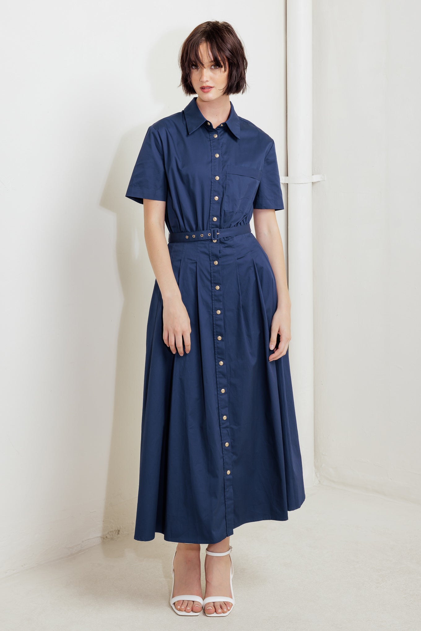 A solid woven midi dress featuring collar, short sleeve, front pocket, button down, self-belt and full skirt