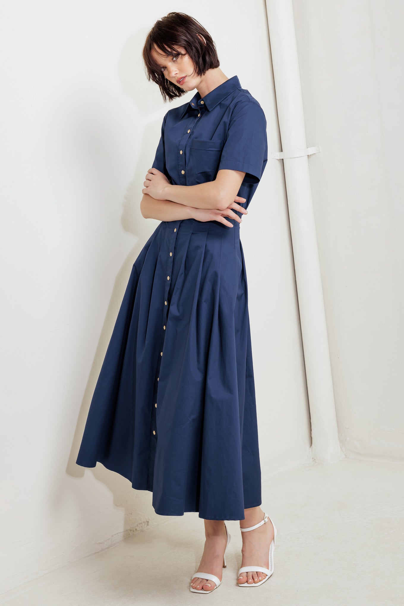 A solid woven midi dress featuring collar, short sleeve, front pocket, button down, self-belt and full skirt