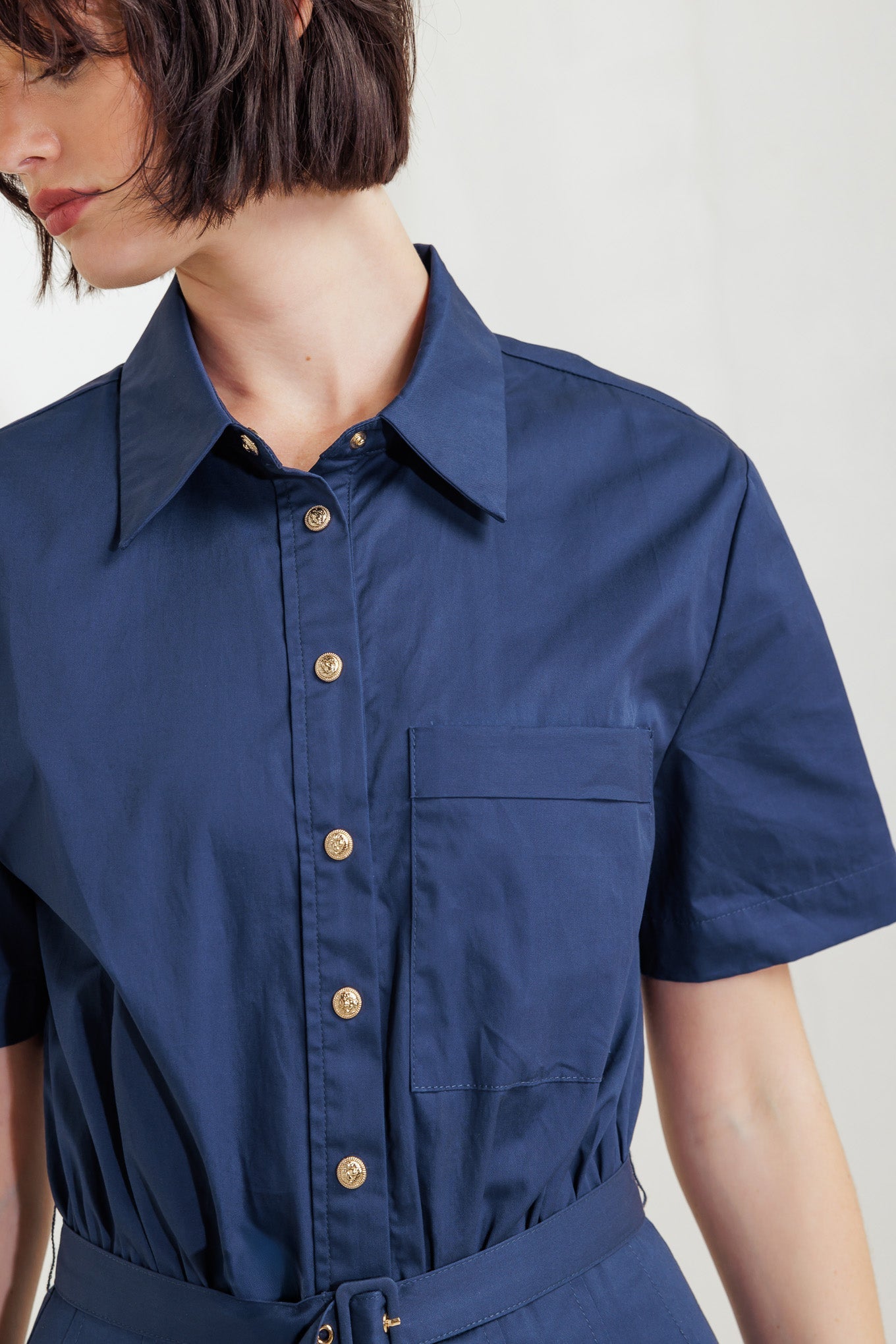 A solid woven midi dress featuring collar, short sleeve, front pocket, button down, self-belt and full skirt