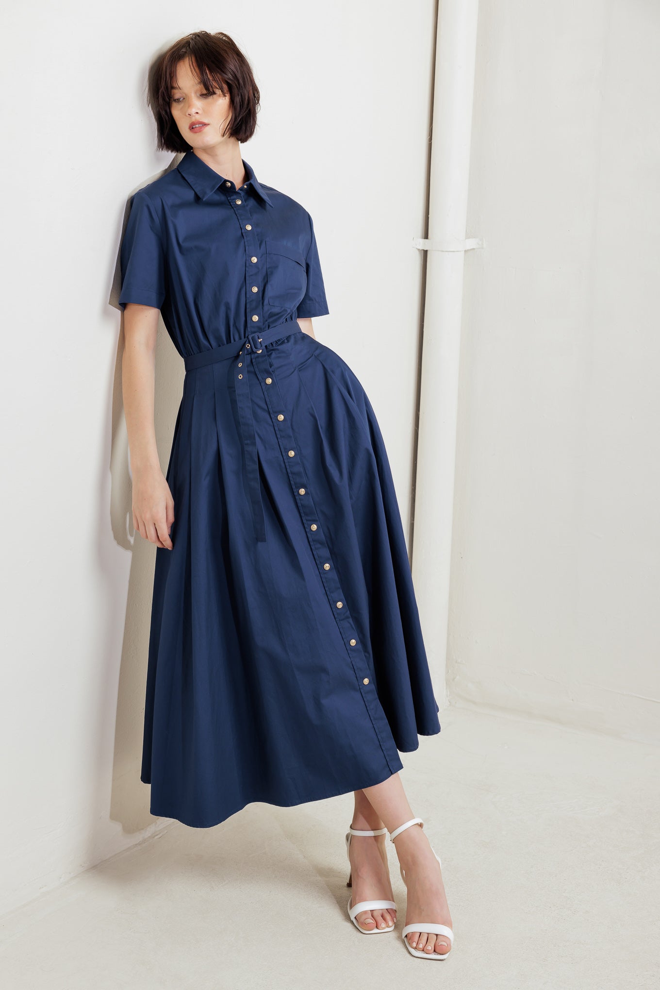 A solid woven midi dress featuring collar, short sleeve, front pocket, button down, self-belt and full skirt