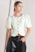 A textured woven top featuring round neckline, short puff sleeve and front button down