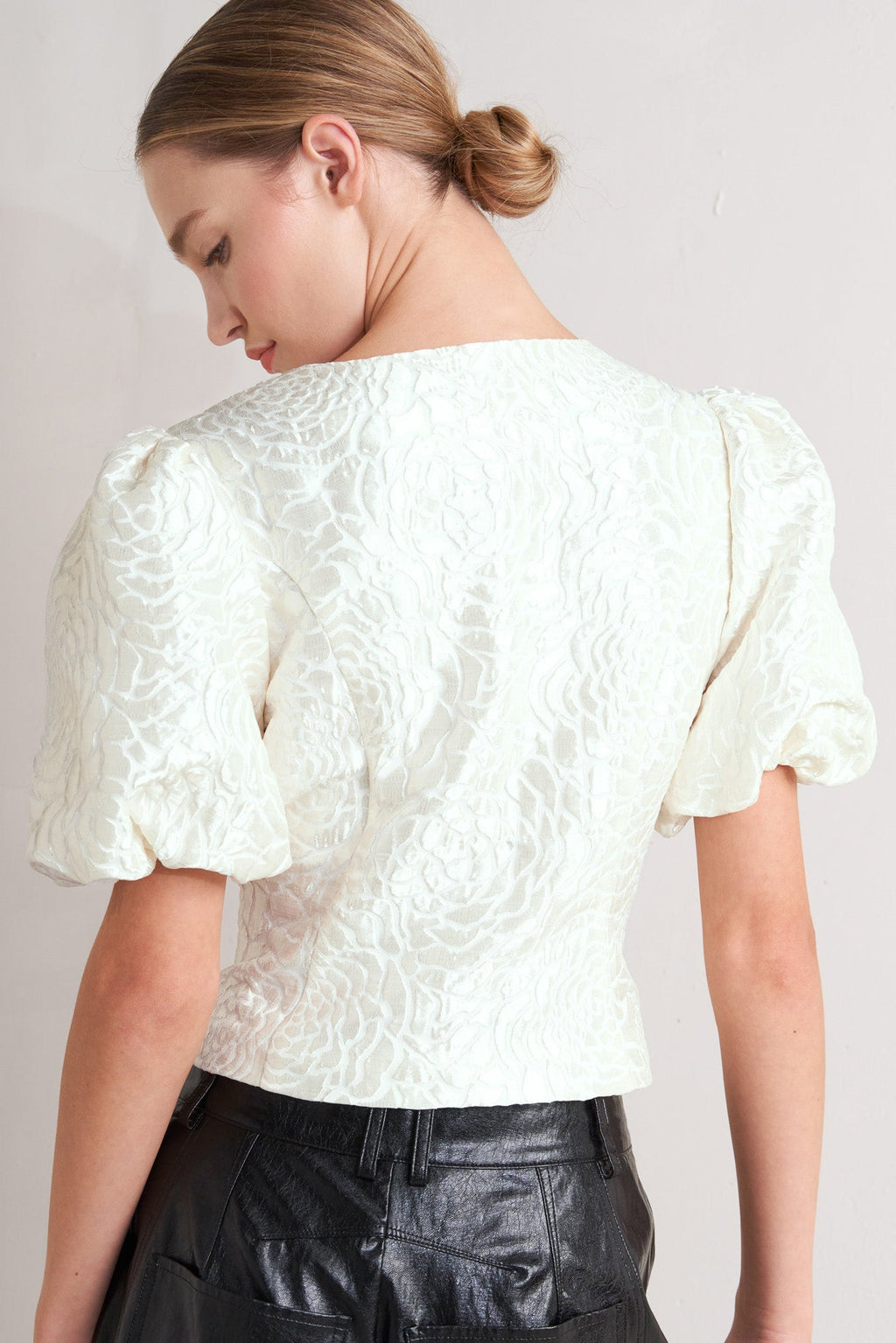 A textured woven top featuring round neckline, short puff sleeve and front button down