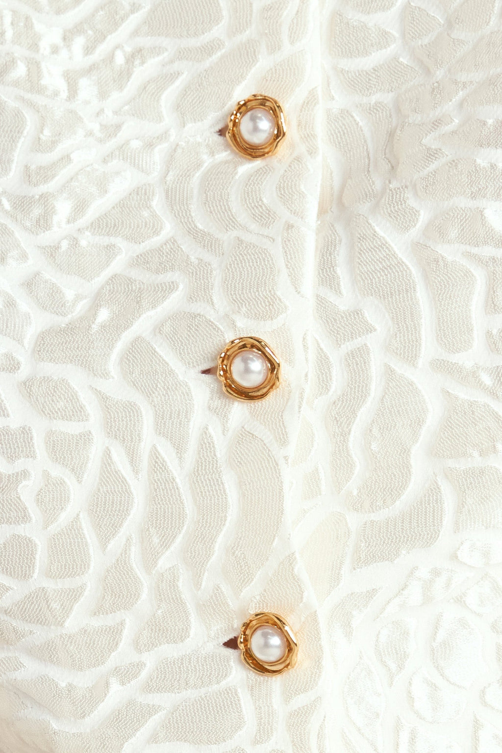 A textured woven top featuring round neckline, short puff sleeve and front button down