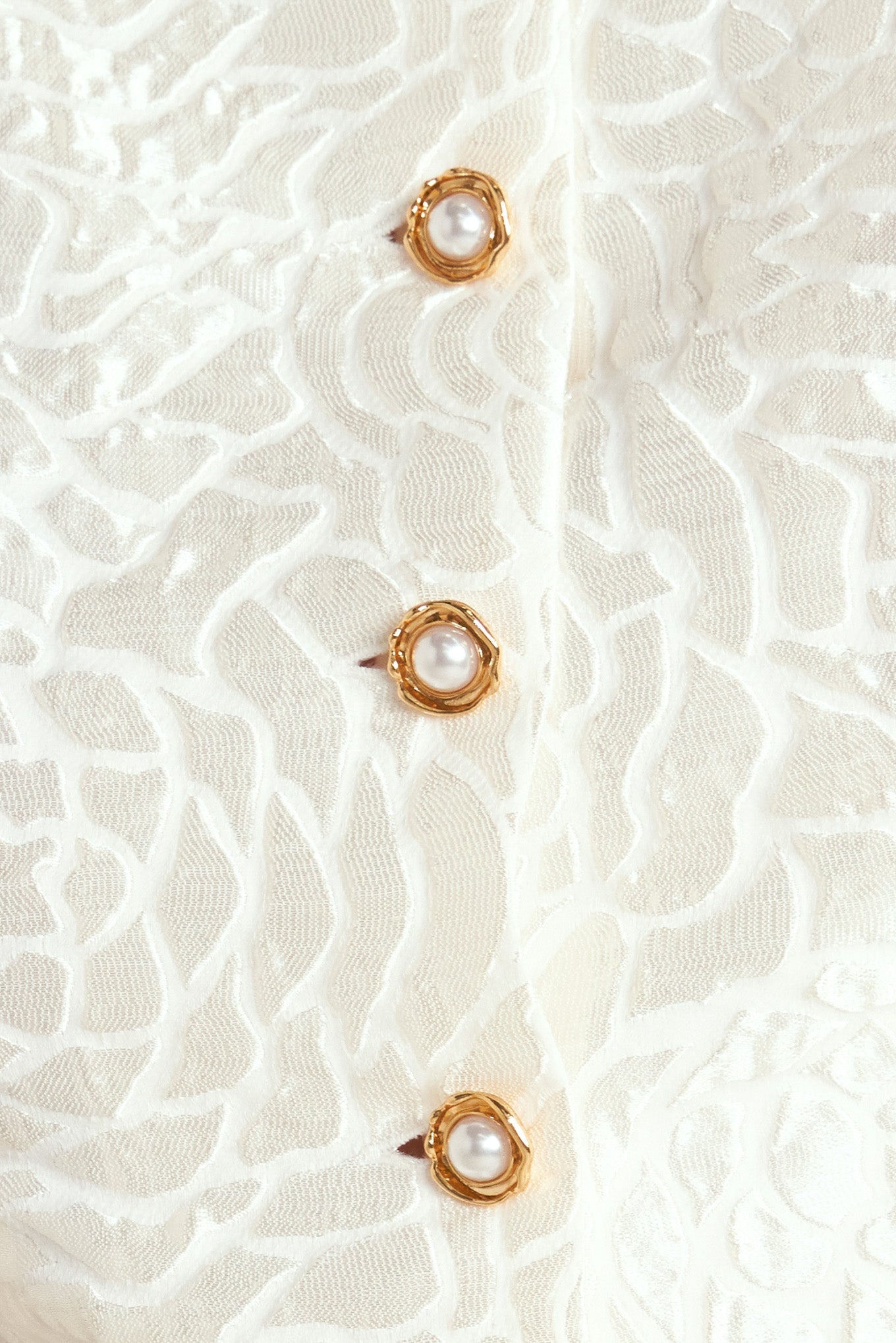 A textured woven top featuring round neckline, short puff sleeve and front button down