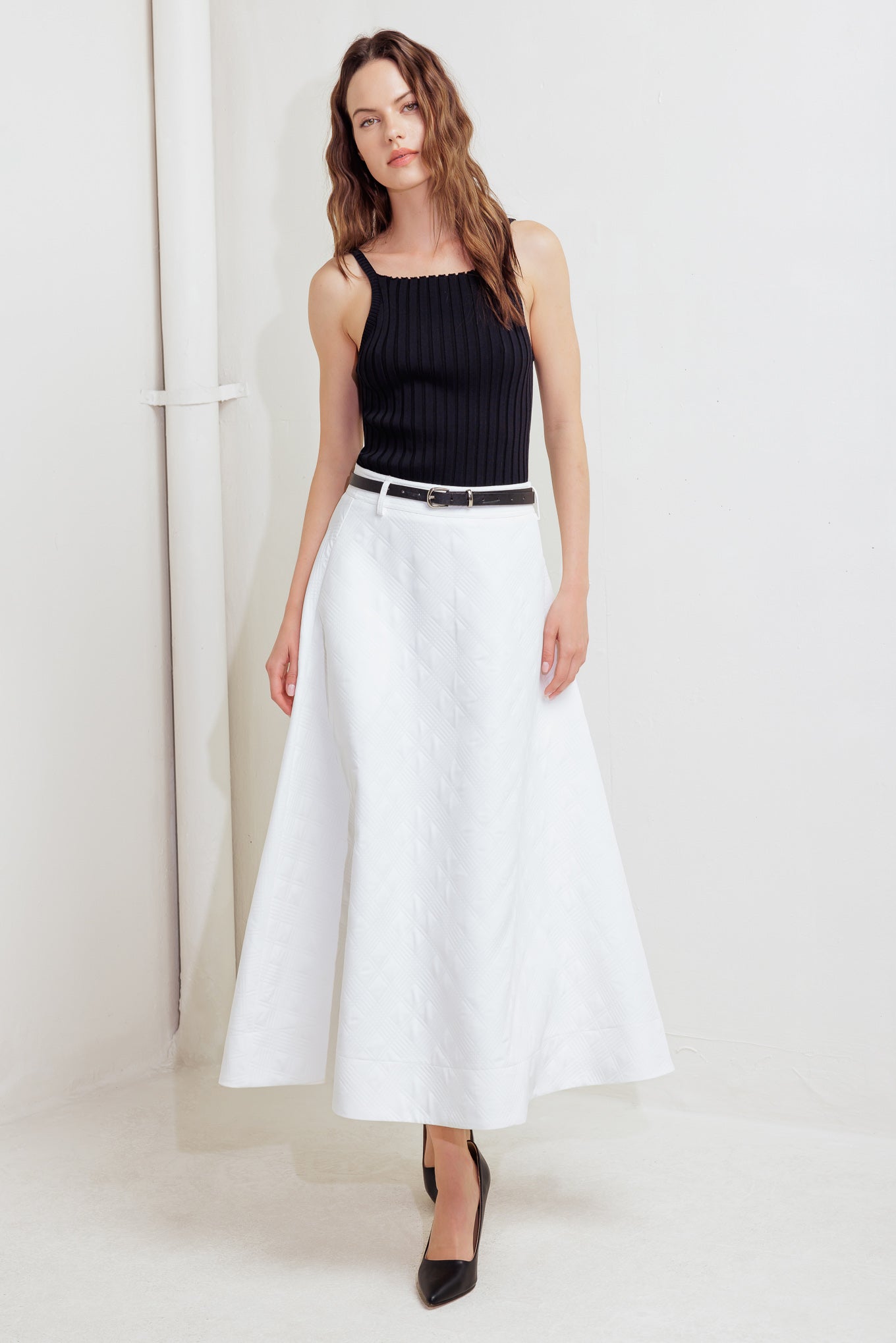 A white, textured woven midi skirt featuring a contrasting belt and back zipper closure