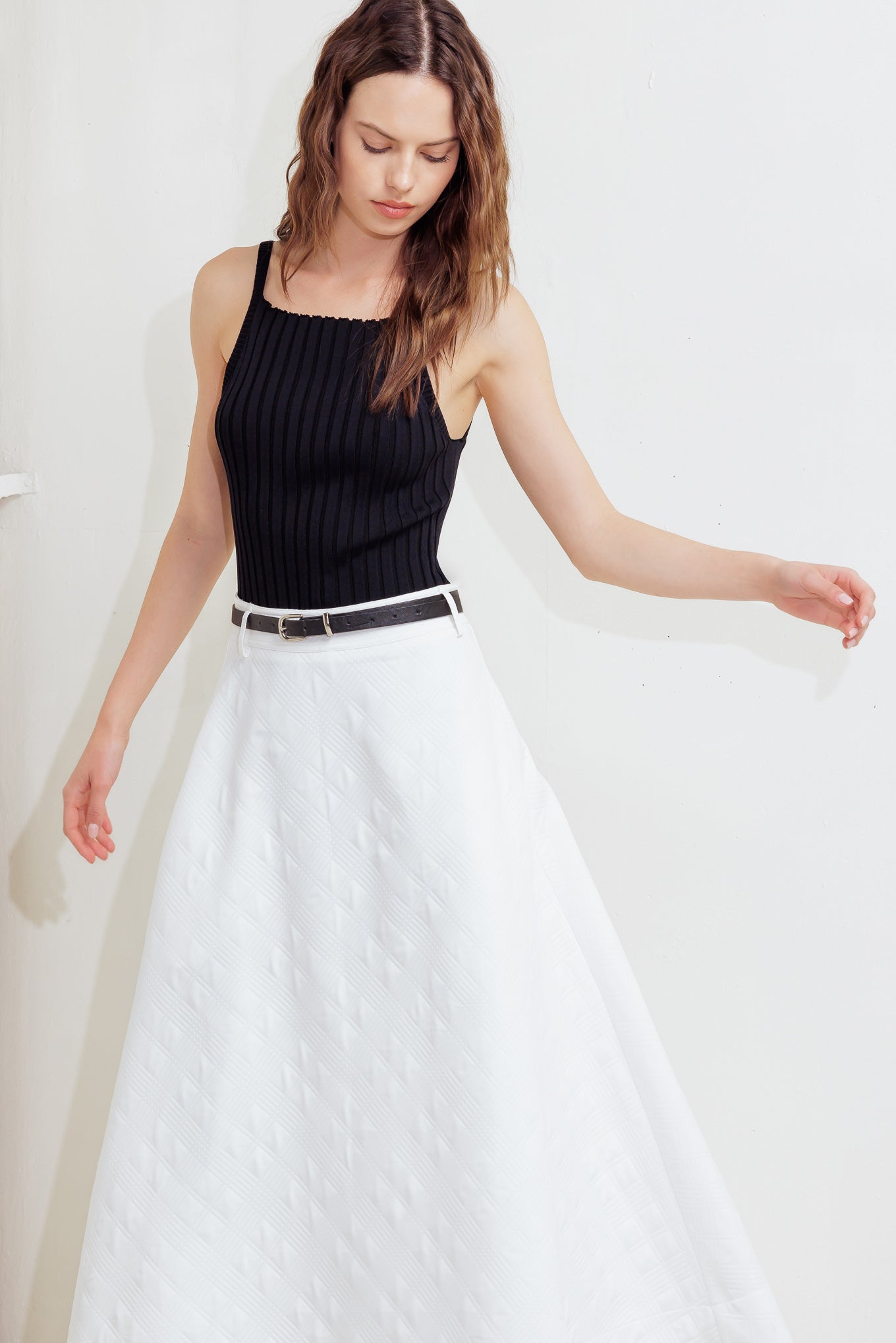 A white, textured woven midi skirt featuring a contrasting belt and back zipper closure