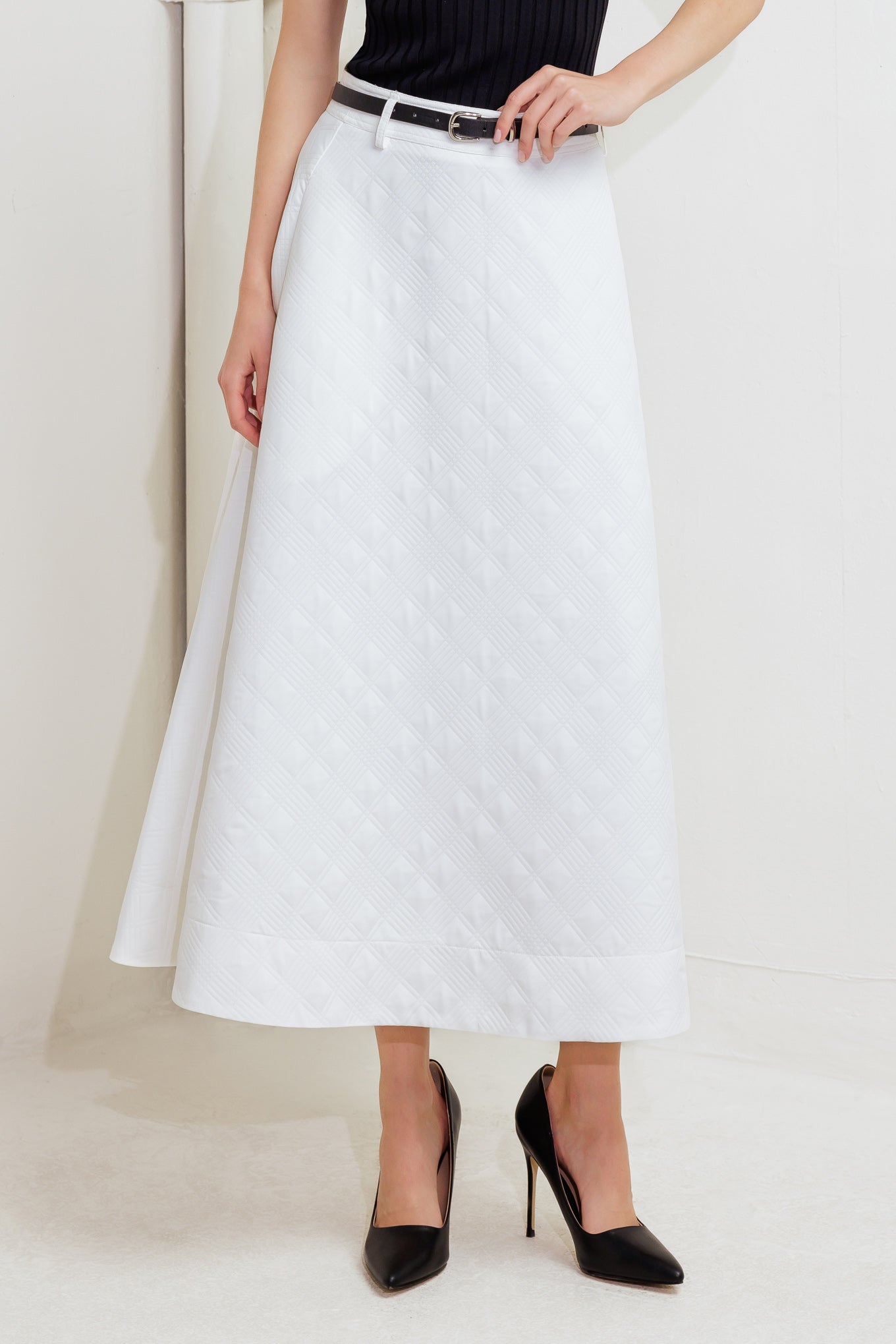 A white, textured woven midi skirt featuring a contrasting belt and back zipper closure