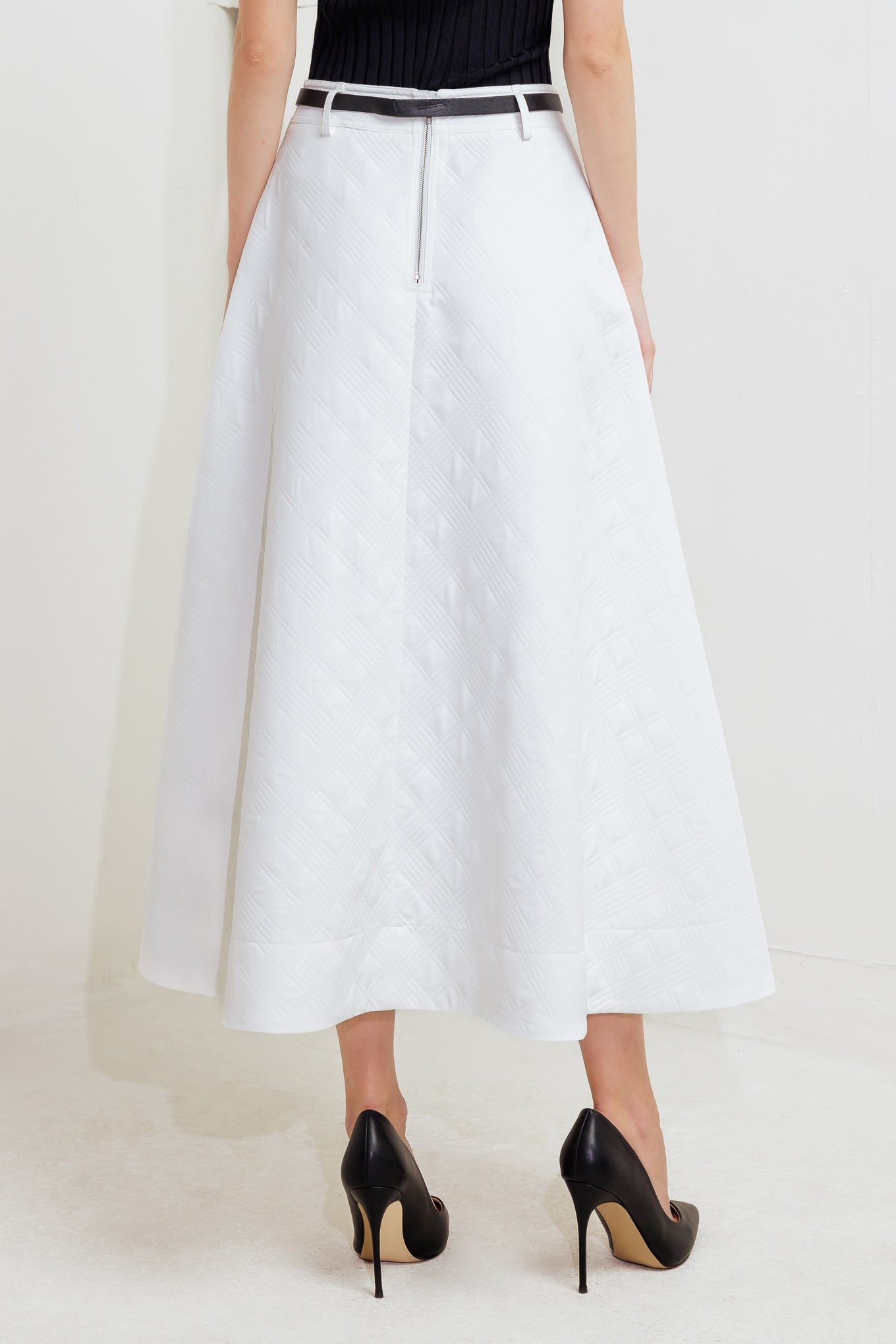 A white, textured woven midi skirt featuring a contrasting belt and back zipper closure