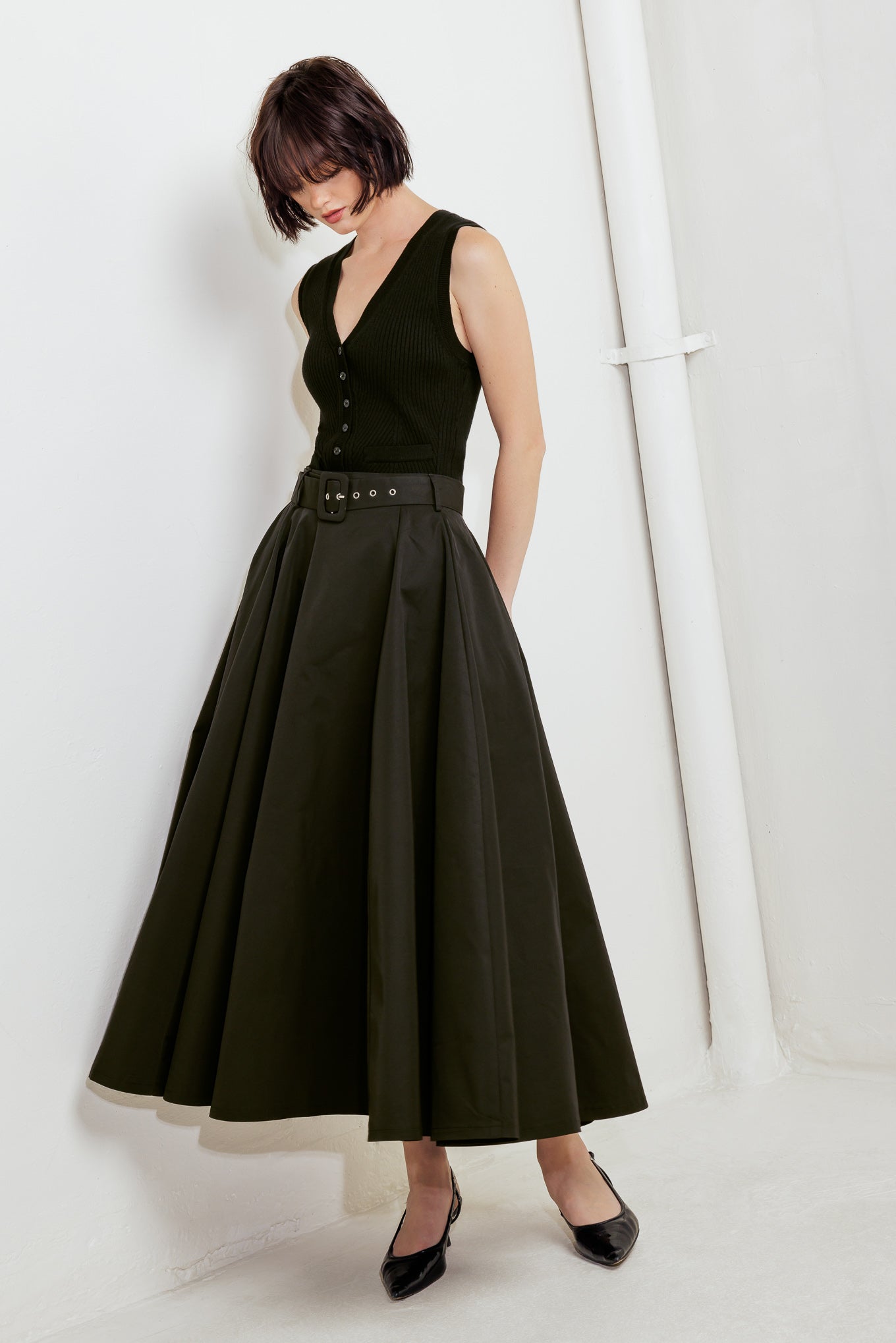 A solid black woven full midi skirt featuring self-belt and side zipper closure