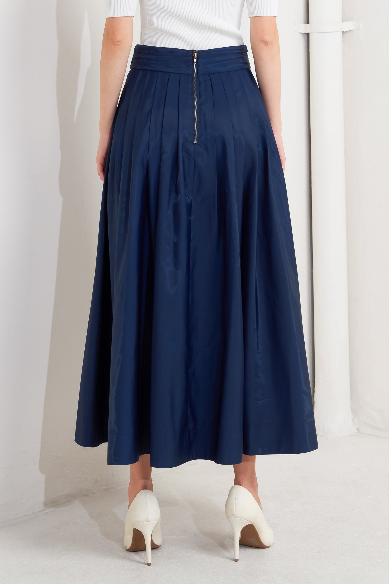 A solid navy woven pleated midi skirt with back zipper.