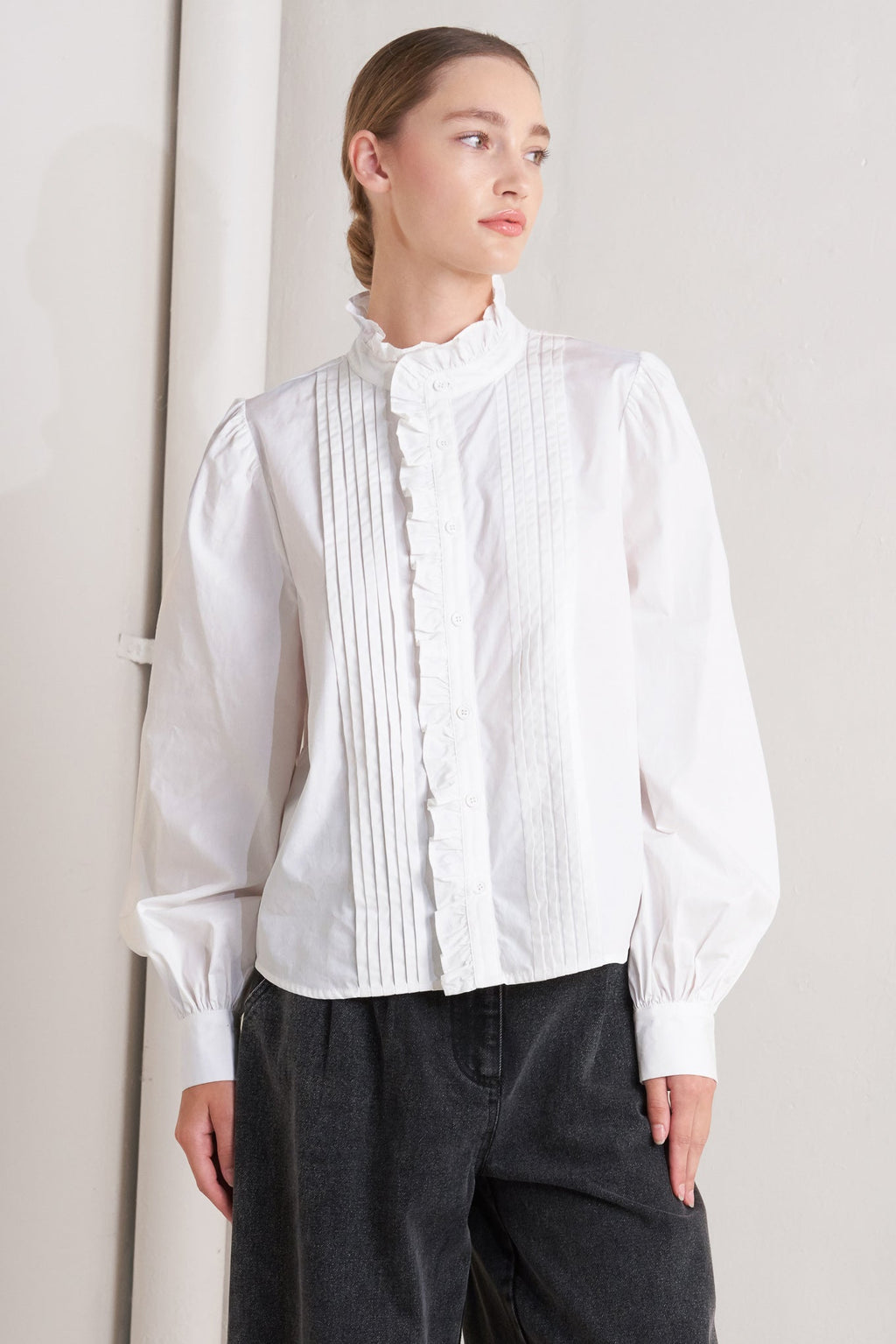 solid woven top featuring ruffled high neckline, long sleeve and front button down closure