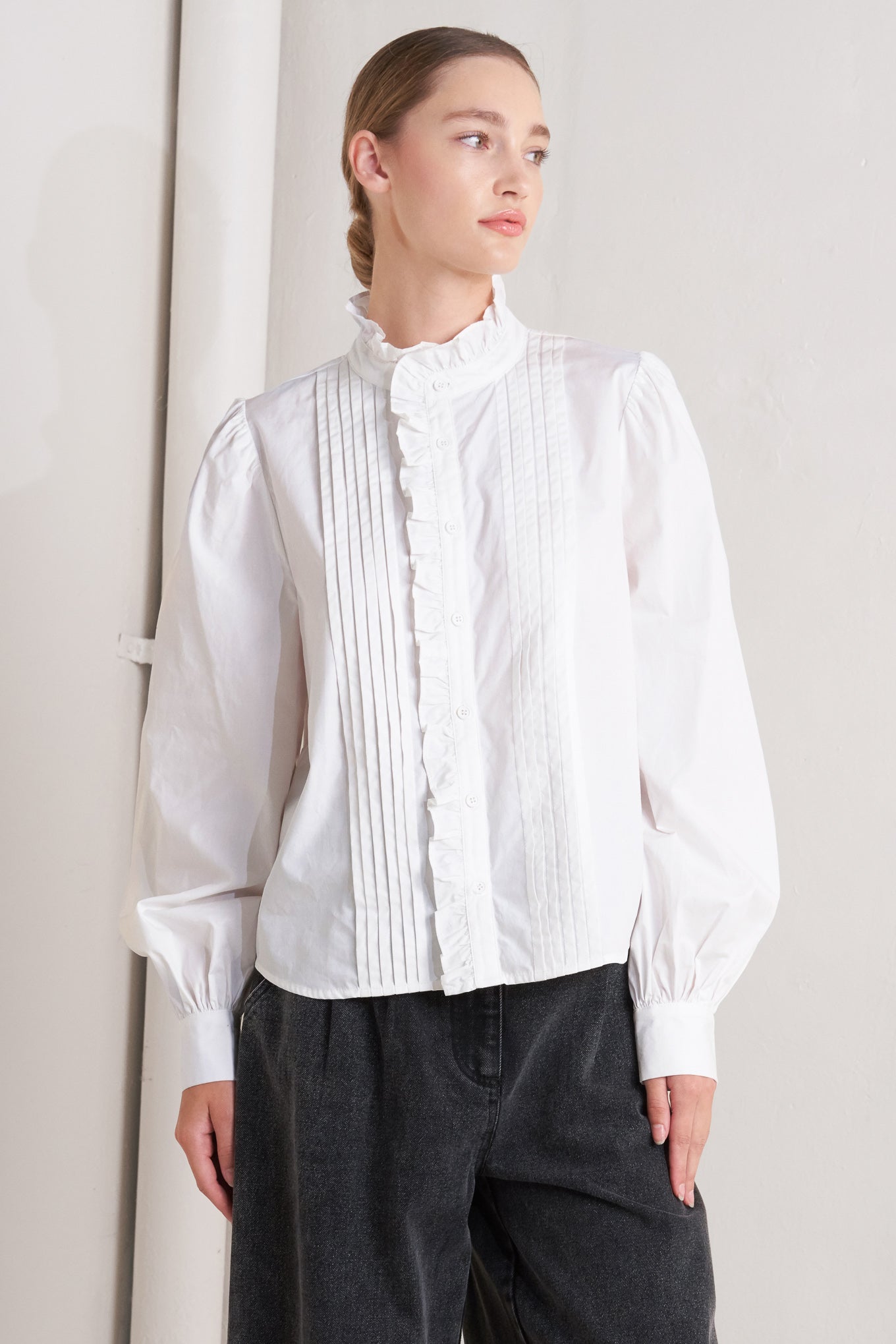 solid woven top featuring ruffled high neckline, long sleeve and front button down closure
