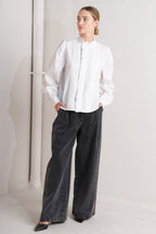 solid woven top featuring ruffled high neckline, long sleeve and front button down closure