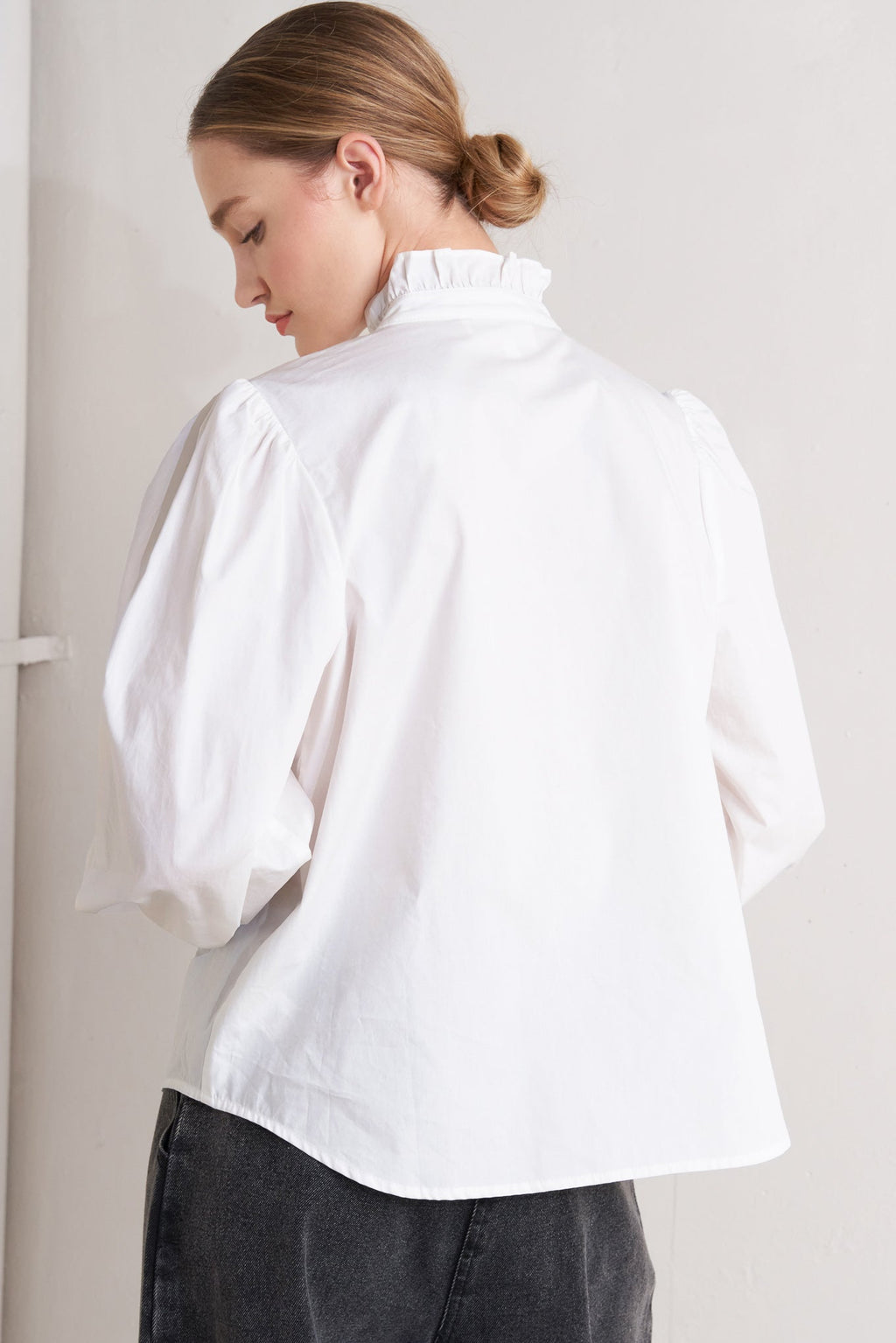 solid woven top featuring ruffled high neckline, long sleeve and front button down closure