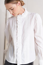 solid woven top featuring ruffled high neckline, long sleeve and front button down closure