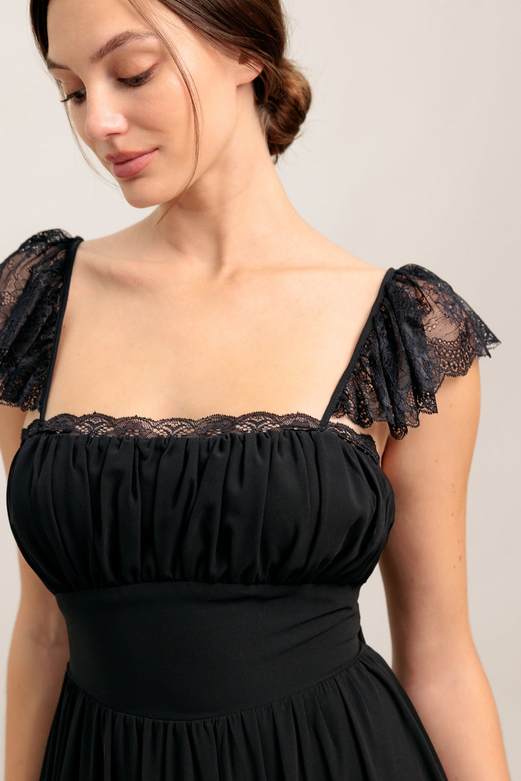 A solid black woven maxi dress featuring straight neckline with lace edge, waist yoke, tiered skirt, bare back with tie closure