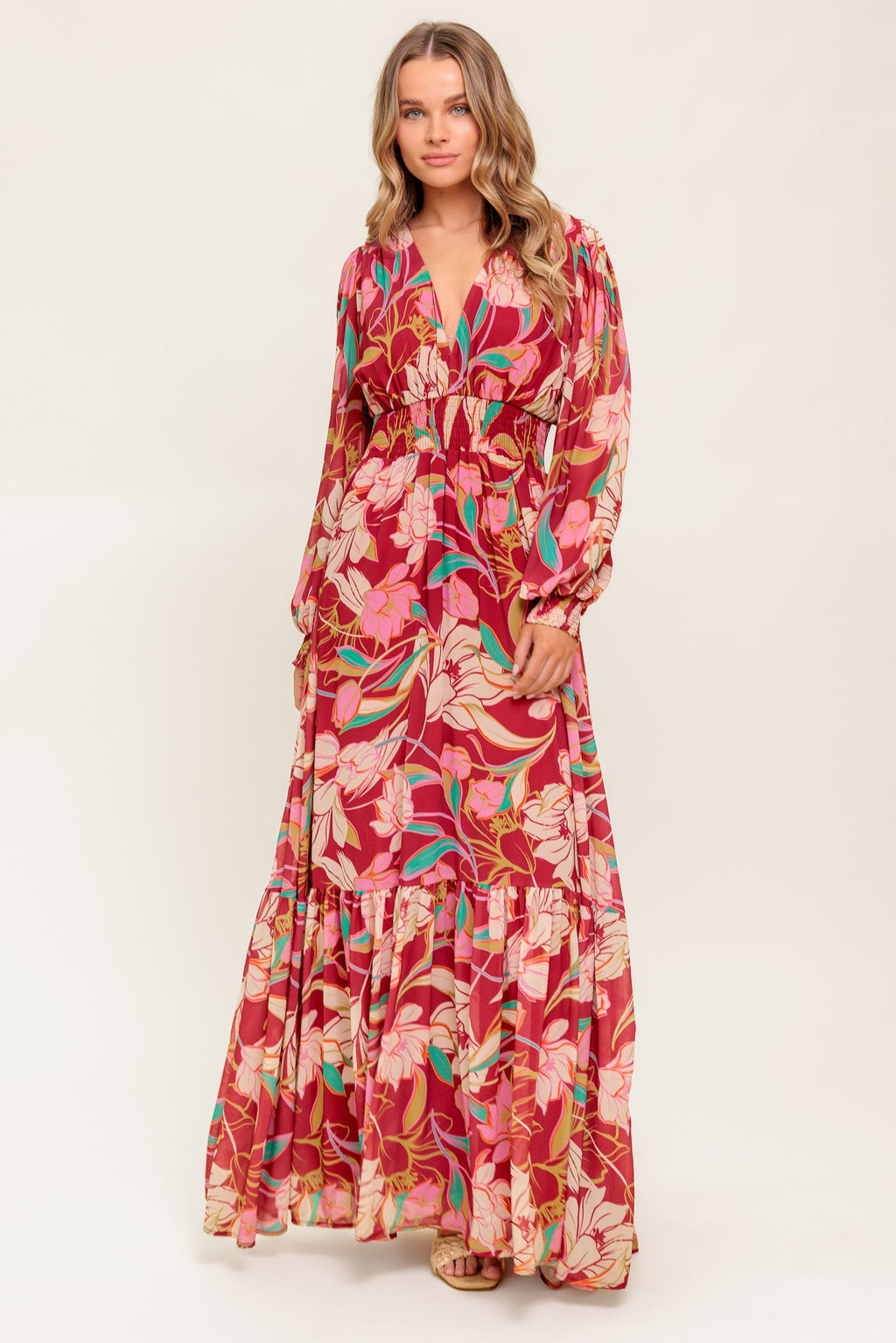 A printed woven maxi dress featuring V neckline, long sleeve with smocked cuff, smocked waist band and ruffled hemline
