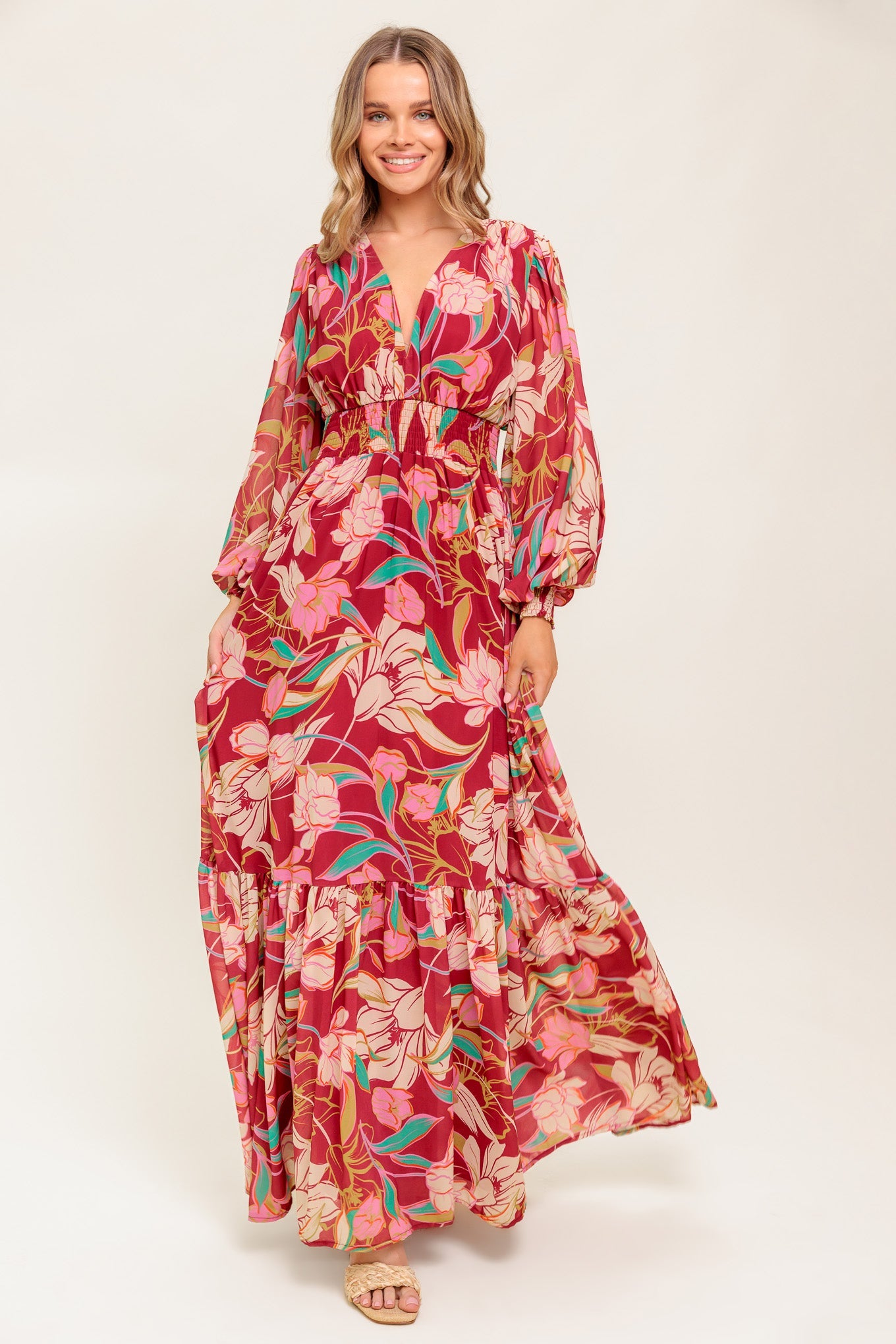 A printed woven maxi dress featuring V neckline, long sleeve with smocked cuff, smocked waist band and ruffled hemline