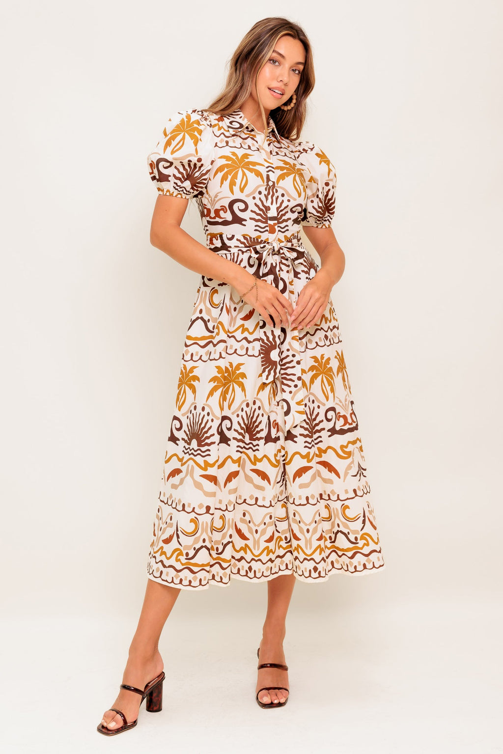 A printed woven midi dress featuring collar, short puff sleeve, button down, self sash and full skirt