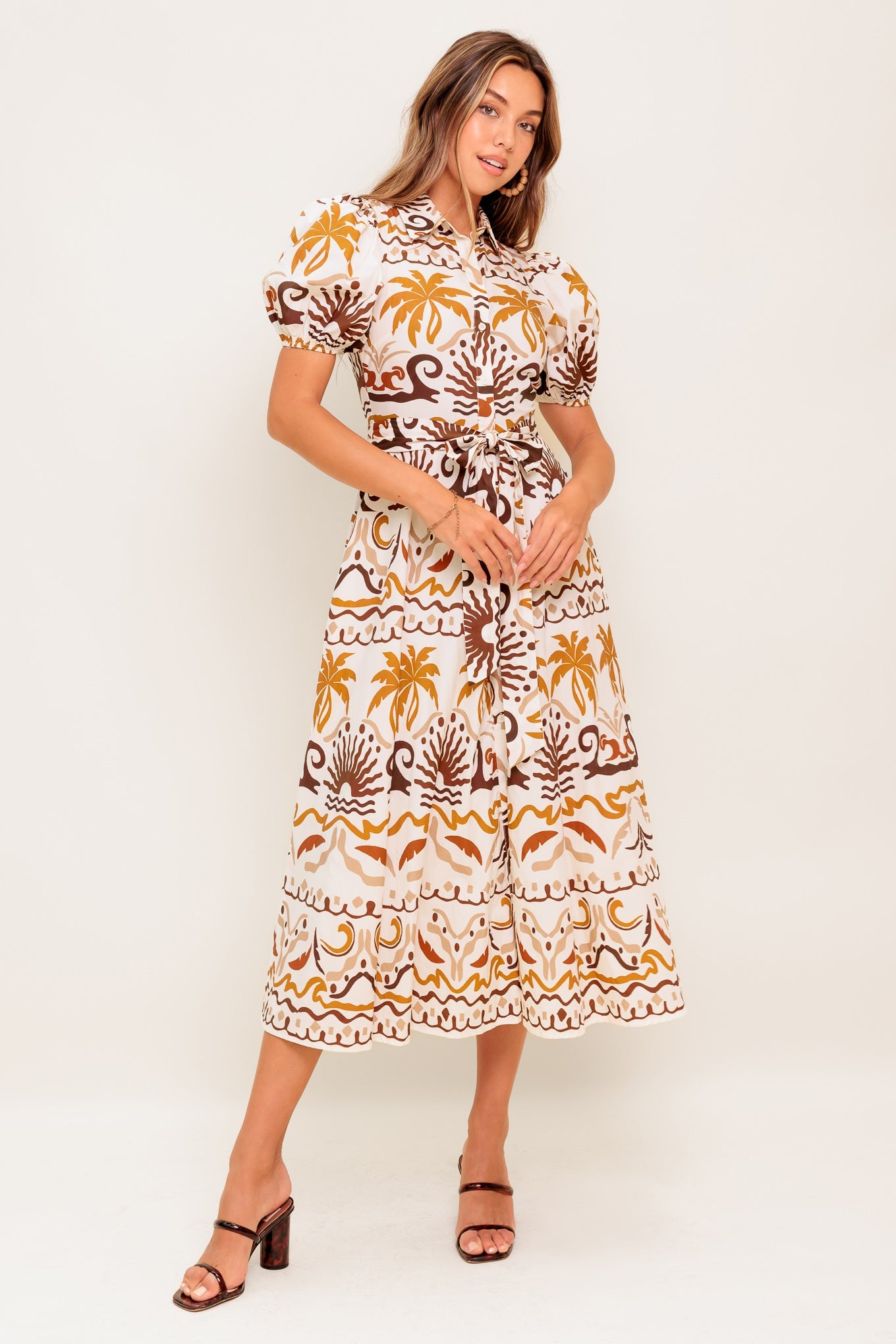 A printed woven midi dress featuring collar, short puff sleeve, button down, self sash and full skirt
