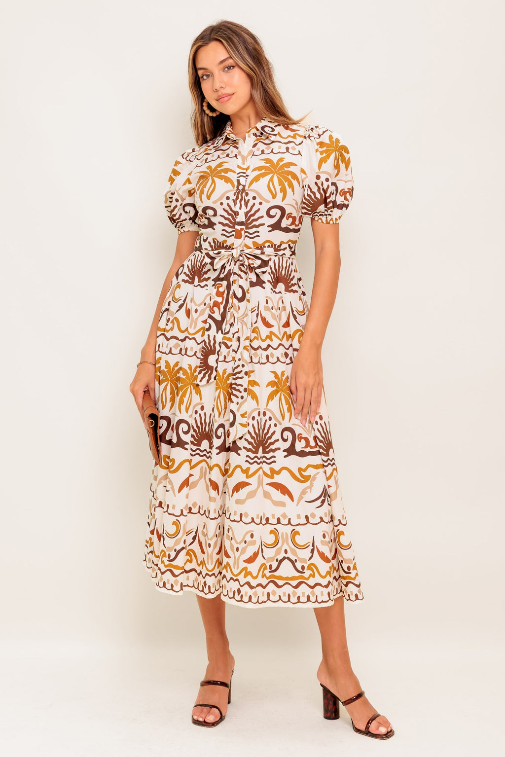 A printed woven midi dress featuring collar, short puff sleeve, button down, self sash and full skirt