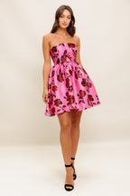 strapless mini dress showcases a pink floral pattern on woven fabric, designed with a full skirt and secured by a back zipper closure.