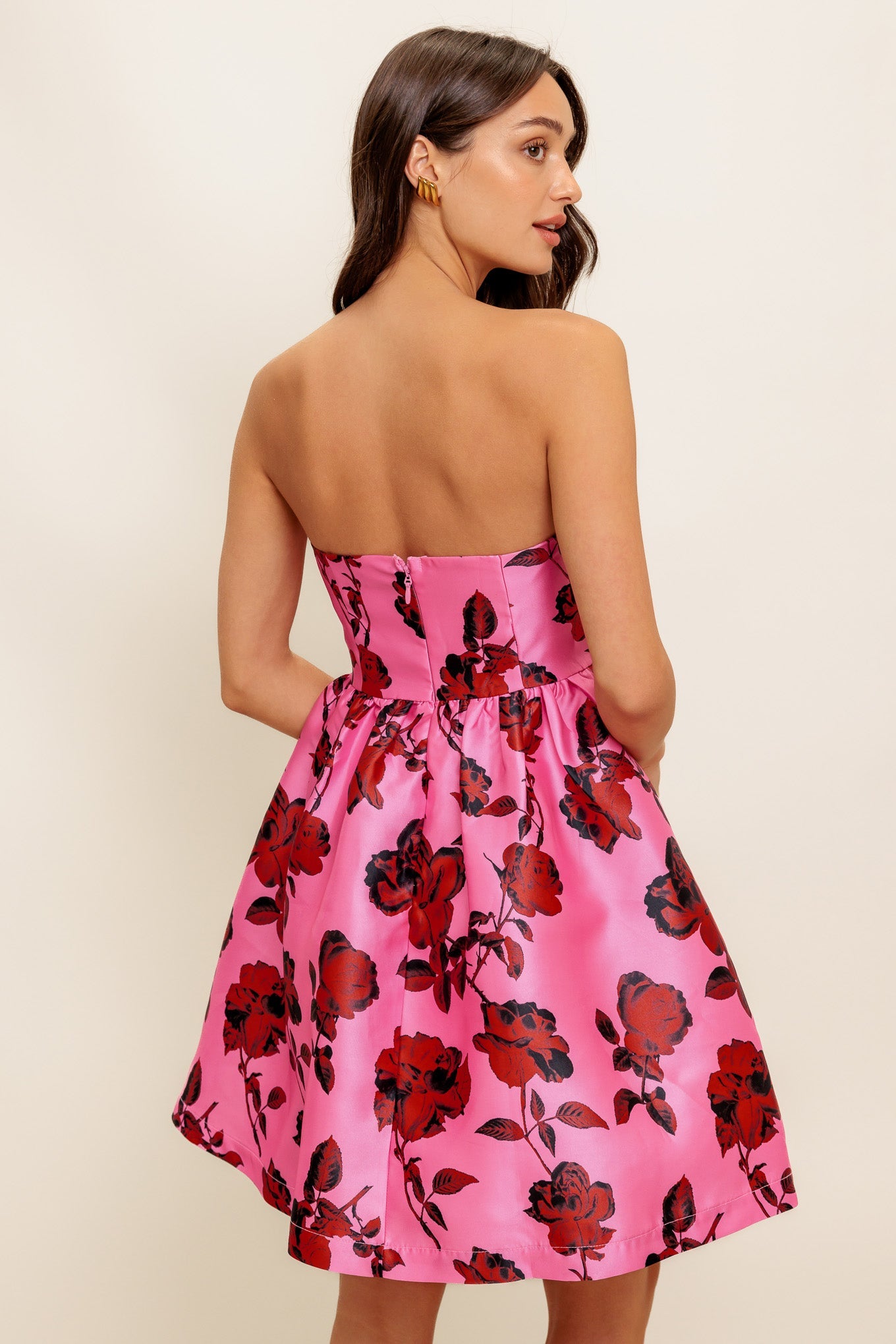 strapless mini dress showcases a pink floral pattern on woven fabric, designed with a full skirt and secured by a back zipper closure.