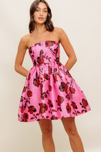 strapless mini dress showcases a pink floral pattern on woven fabric, designed with a full skirt and secured by a back zipper closure.
