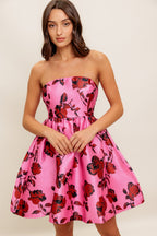 strapless mini dress showcases a pink floral pattern on woven fabric, designed with a full skirt and secured by a back zipper closure.