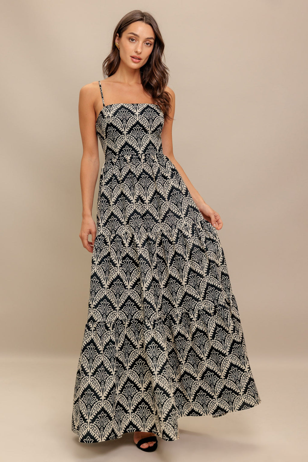 A printed black & ivory woven maxi dress featuring sweetheart neckline, straps, tiered skirt and smocked back bodice