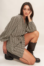 A textured woven mini dress featuring ruffled high neck with V front neckline and long sleeve