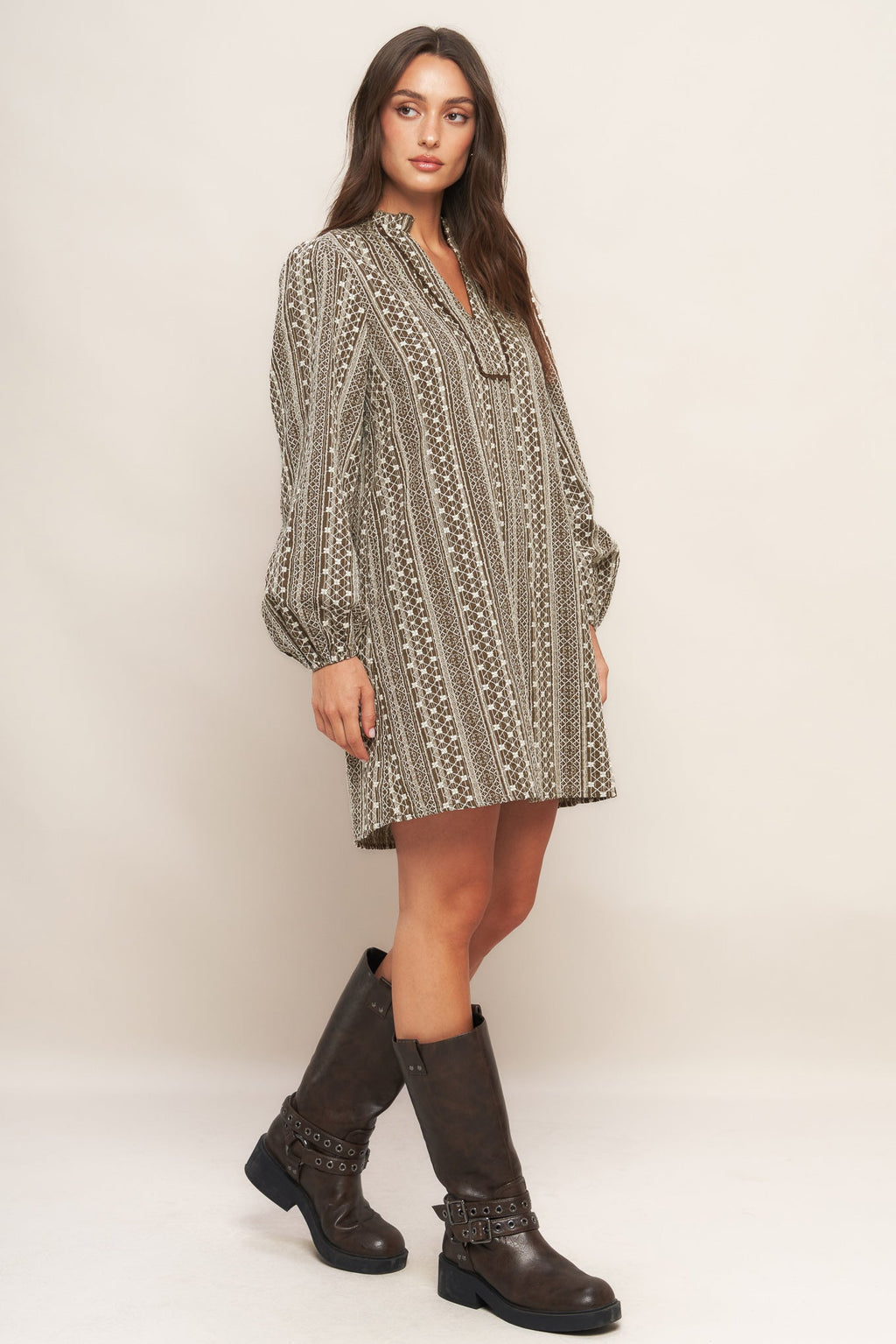 A textured woven mini dress featuring ruffled high neck with V front neckline and long sleeve
