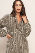 A textured woven mini dress featuring ruffled high neck with V front neckline and long sleeve
