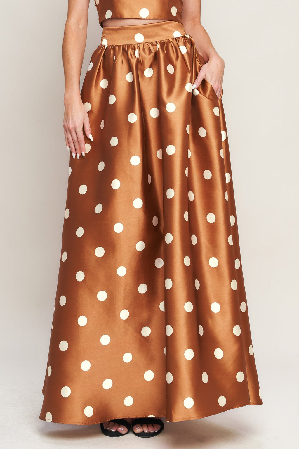 A polka dot printed woven full maxi skirt with size pocket and back zipper closure.