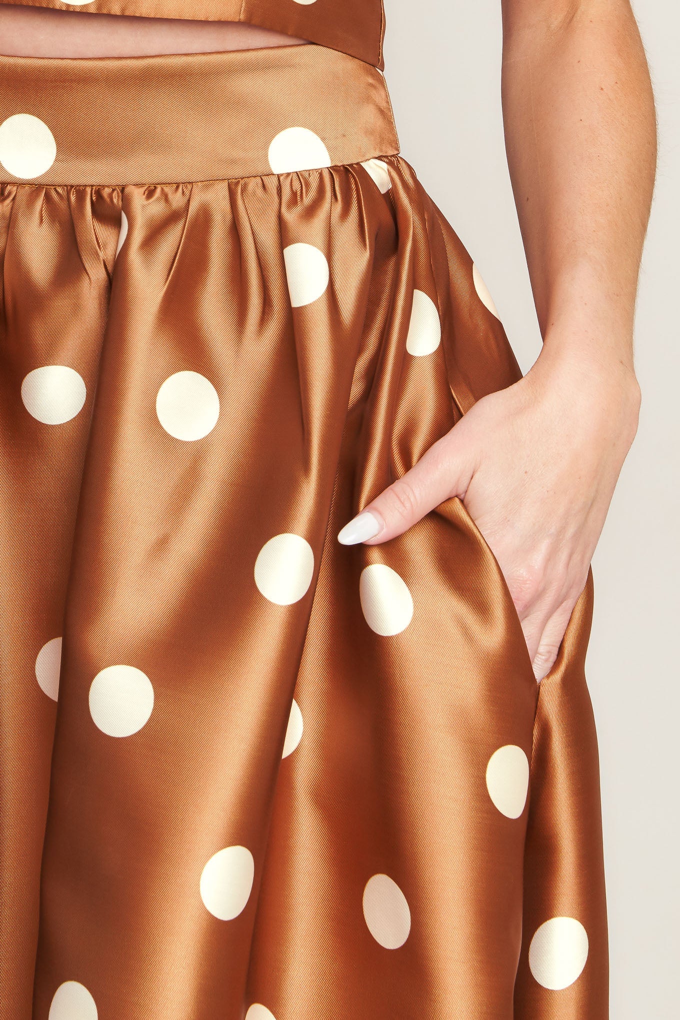 A polka dot printed woven full maxi skirt with size pocket and back zipper closure.