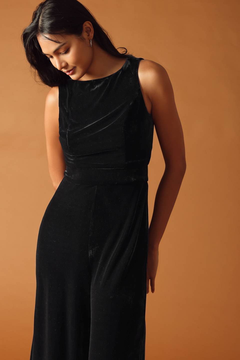 Woman wearing a black sleeveless dress against a brown background