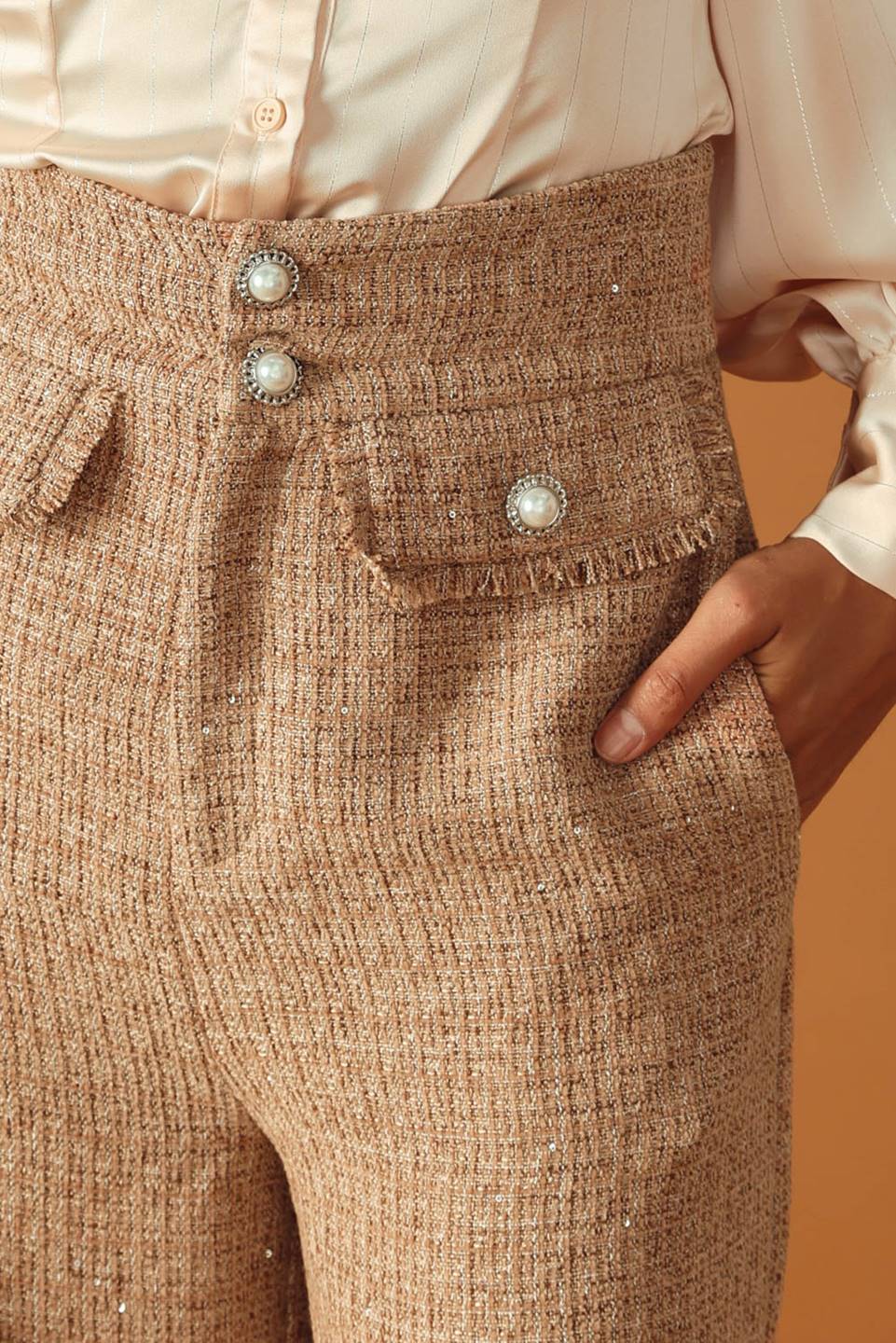 A tweed pant featuring front closure, jewel button and pockets