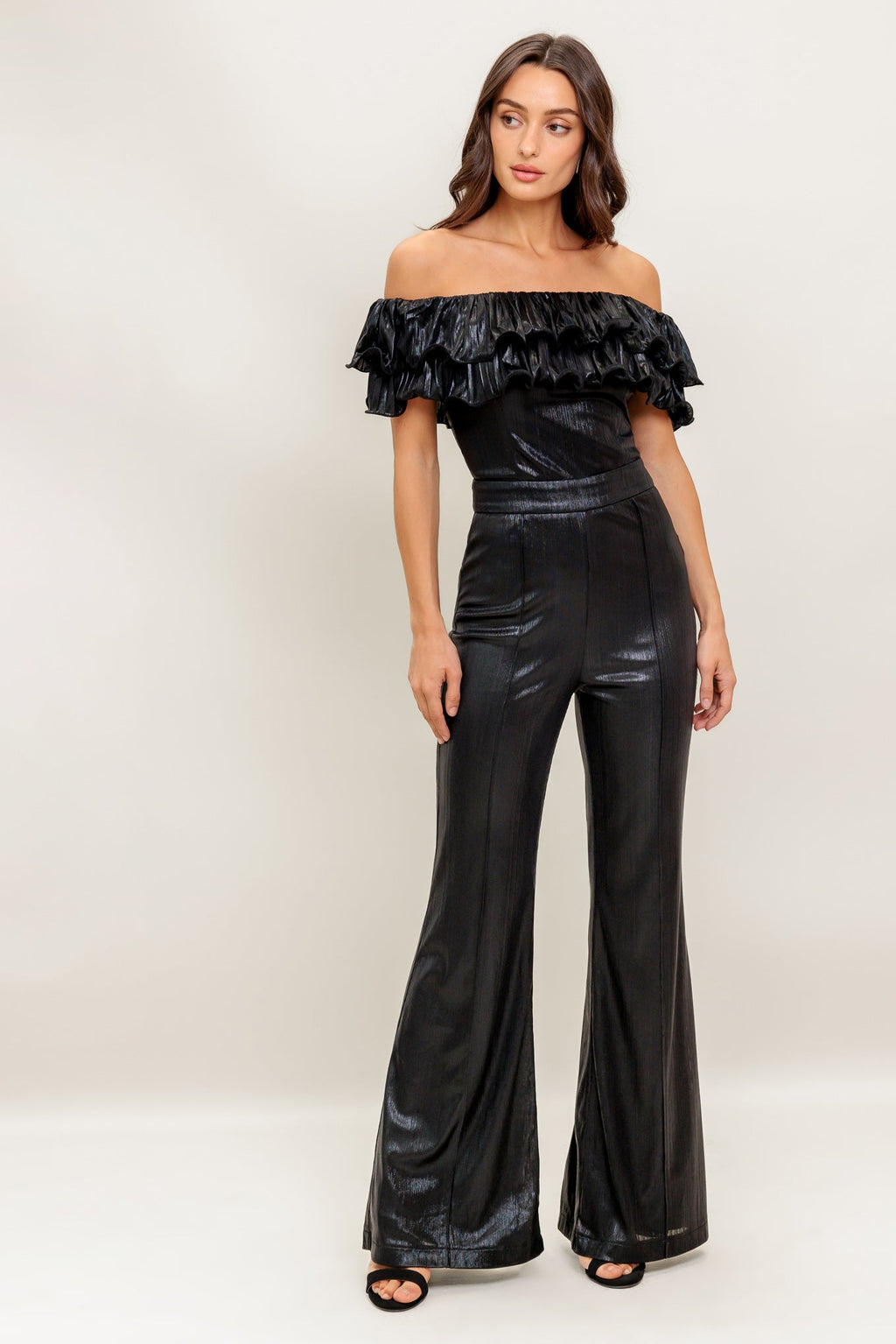 A black coated woven jumpsuit featuring off shoulder neckline, double layer pleated flounce, flare leg and back zipper closure