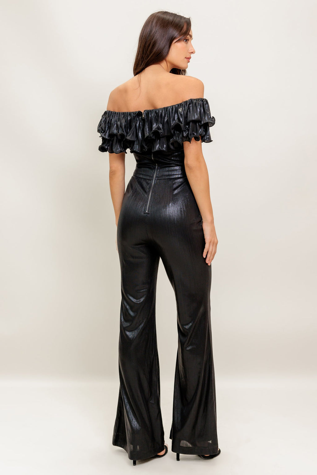 A black coated woven jumpsuit featuring off shoulder neckline, double layer pleated flounce, flare leg and back zipper closure