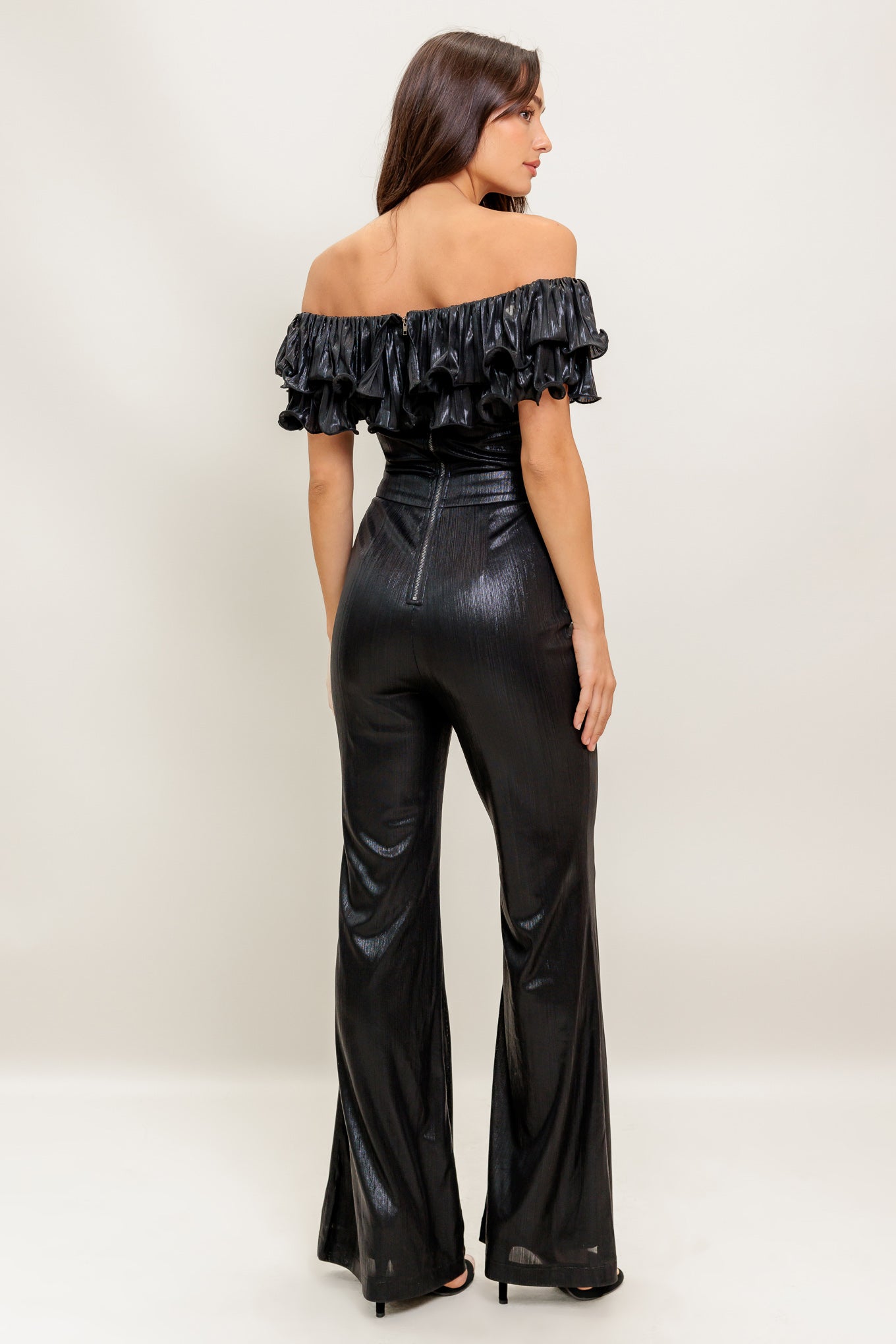 A black coated woven jumpsuit featuring off shoulder neckline, double layer pleated flounce, flare leg and back zipper closure