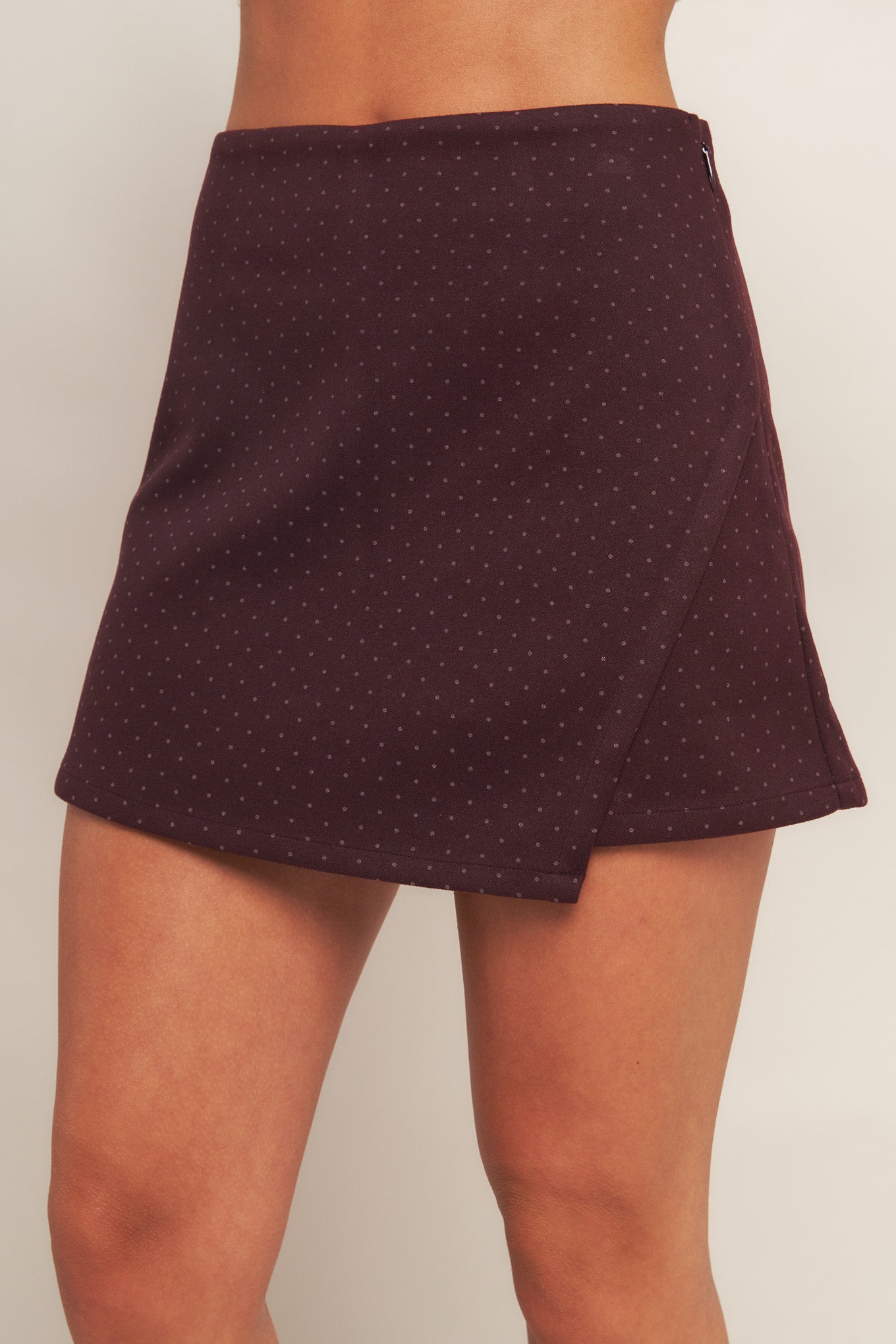 A woven burgundy skort featuring front flap and side zipper closure.