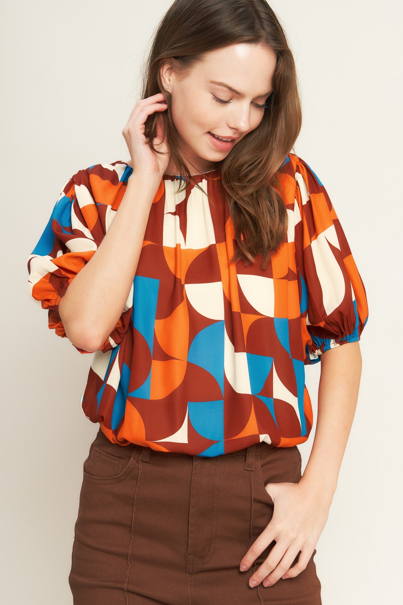 Woman wearing a colorful patterned blouse against a plain background