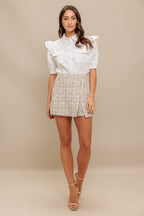 A solid white woven top featuring collar, snap button down, ruffled shoulder, short puff sleeve and pockets