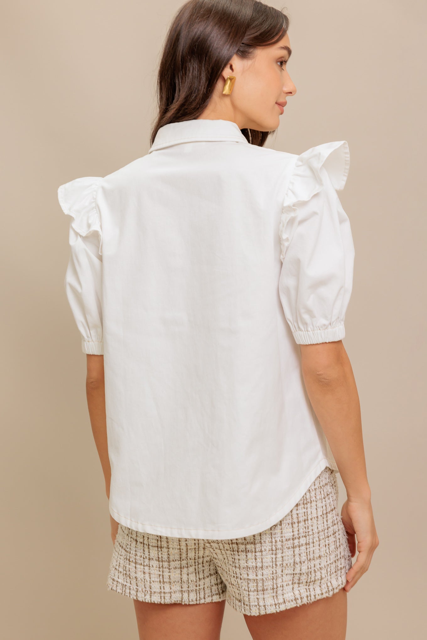 A solid white woven top featuring collar, snap button down, ruffled shoulder, short puff sleeve and pockets